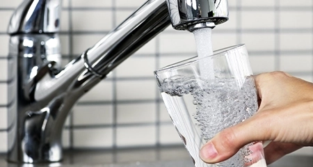 glass of water being filled at kitchen sink