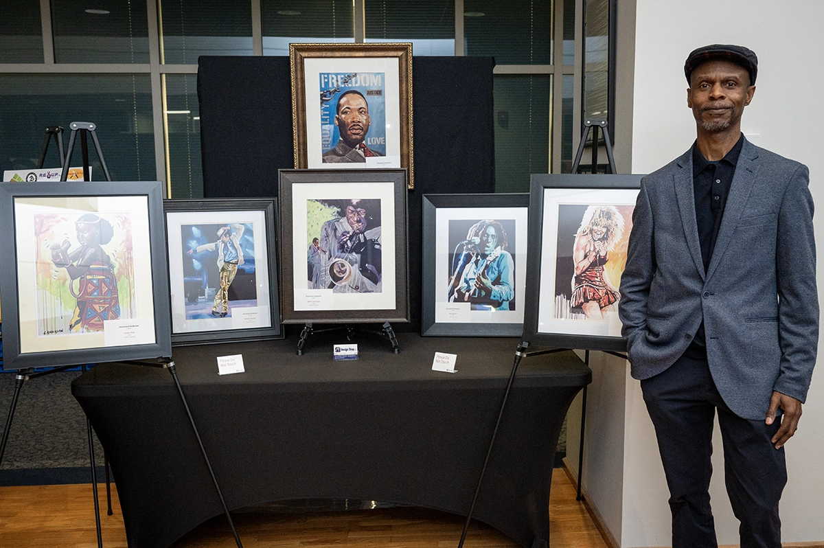 African-american man standing next to his paintings