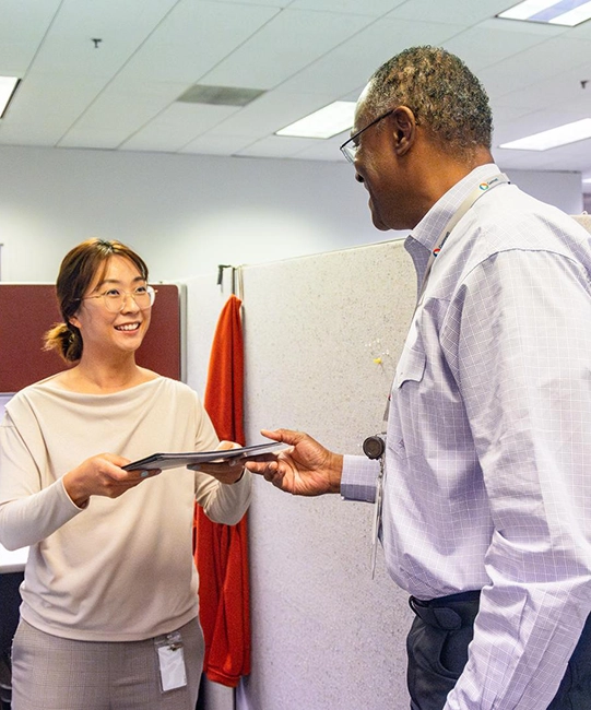 A man and a woman talking and passing papers