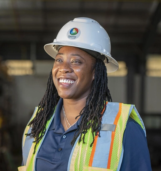 Smiling woman wearing a safety helmet and a safety reflective vest